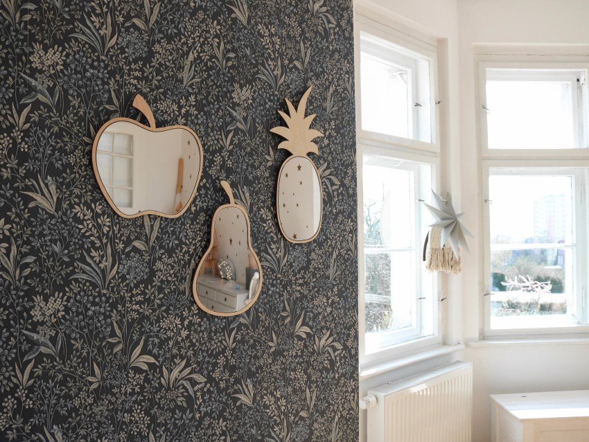 1. Apple-shaped mirror with natural plywood frame on floral wallpaper in a bright room with large windows