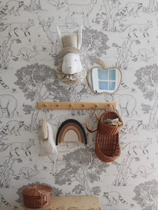 2. Apple-shaped mirror with natural plywood frame on animal-themed wallpaper above wooden hooks and baskets