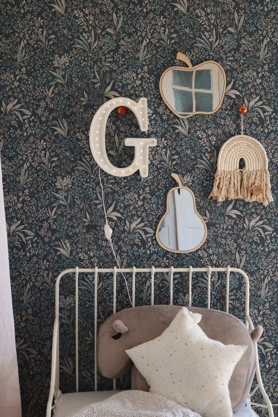 4. Apple-shaped mirror with natural plywood frame on floral wallpaper above a bed with decorative pillows