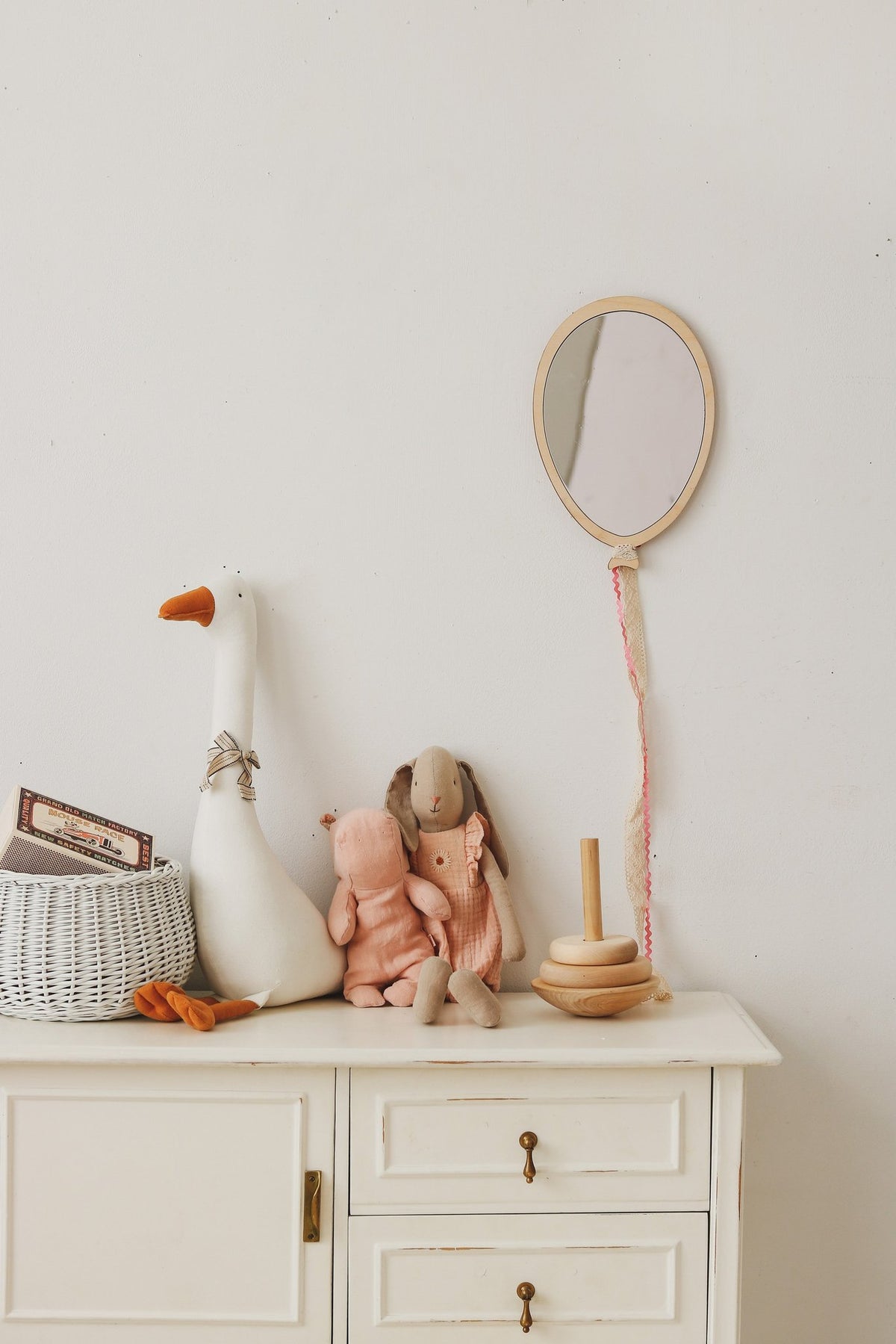 2. Balloon-shaped mirror on wall above white cabinet with plush toys, wicker basket, and wooden stacking toy in kids room
