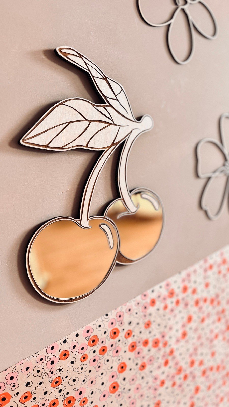 3. Close-up of cherry mirror with gold-tinted acrylic and smooth plywood frame, floral wall accents visible