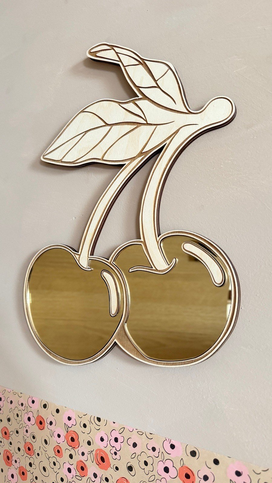 6. Cherry-shaped mirror with gold-tinted acrylic and plywood frame, floral wall pattern in background