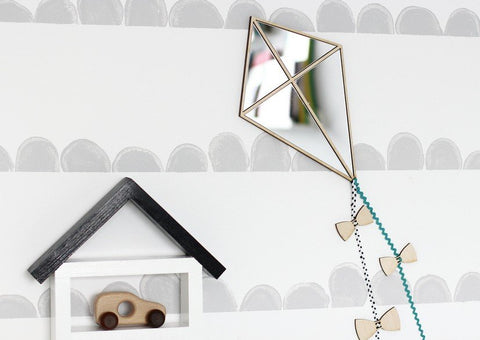 1. Kite-shaped mirror with natural plywood frame and ribbon detail on nursery wall with toy shelf