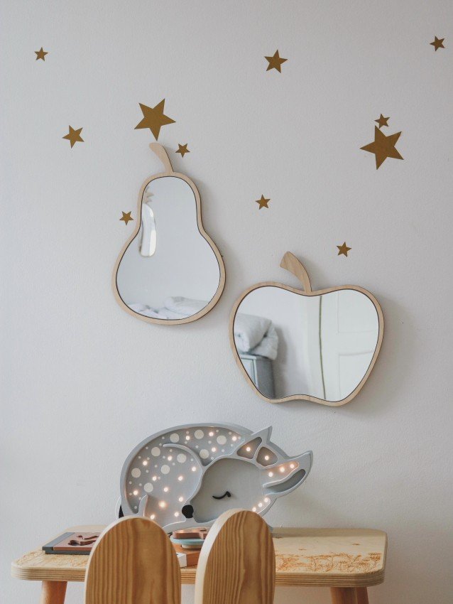 2. Pear and apple-shaped mirrors with plywood frames on white wall with gold star decals above a child's desk.