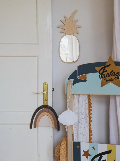 3. Pineapple-shaped mirror with natural plywood frame on wall next to play area with rainbow decor