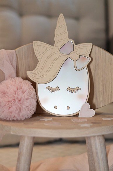 2. Unicorn-shaped mirror with natural plywood frame on wooden chair, surrounded by pink pom-pom and heart decor