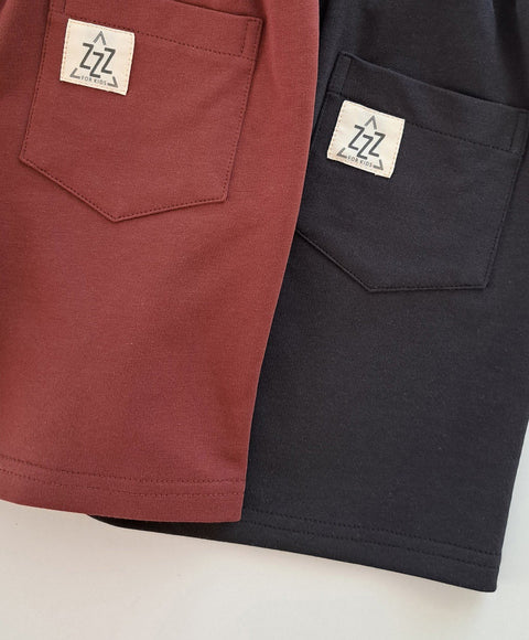 3. Close-up of back pockets on dark antrachite and maroon kids' shorts with Zezuzulla logo patch