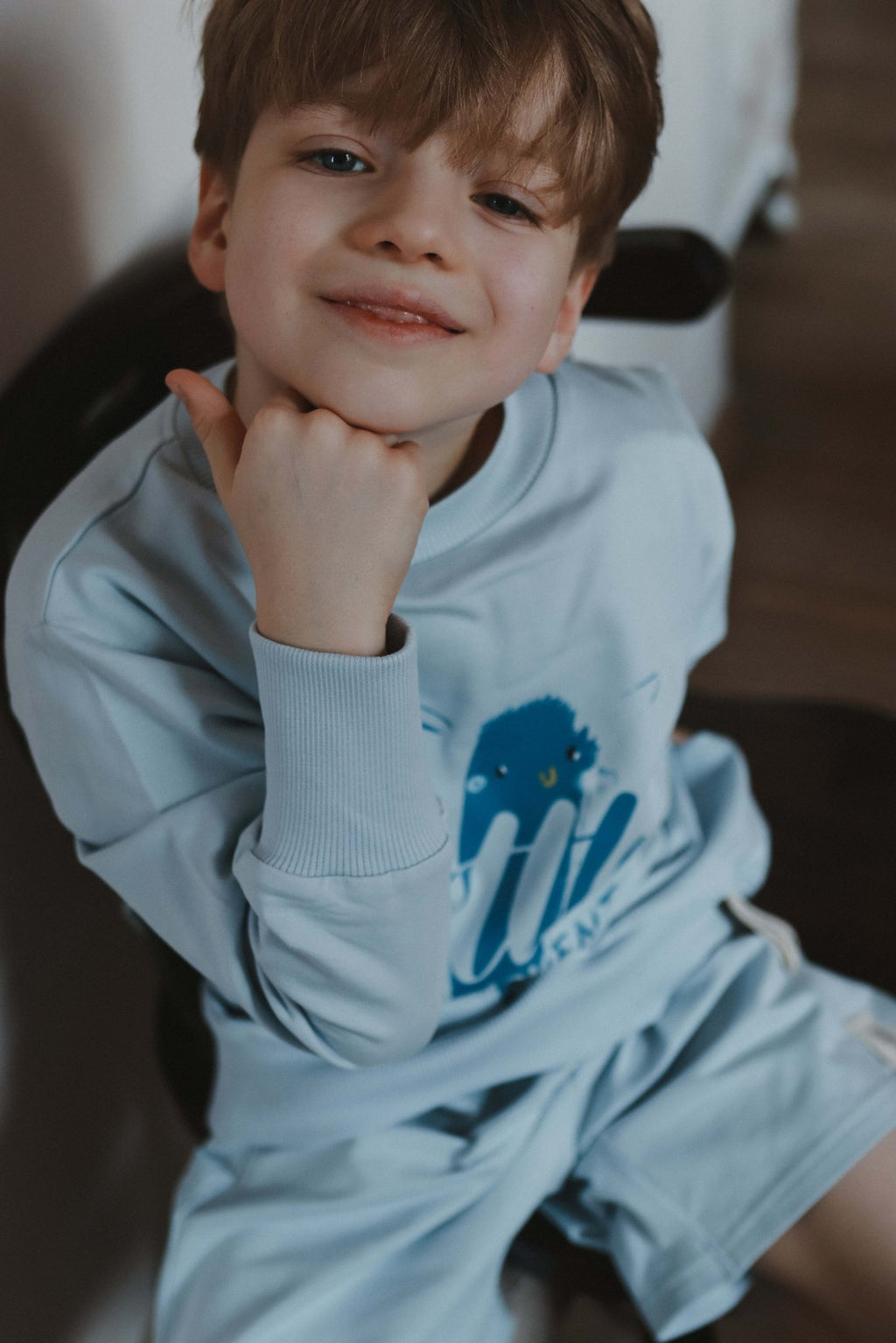 1. Child wearing pastel blue Zezuzulla shorts and matching sweatshirt sitting on a chair indoors
