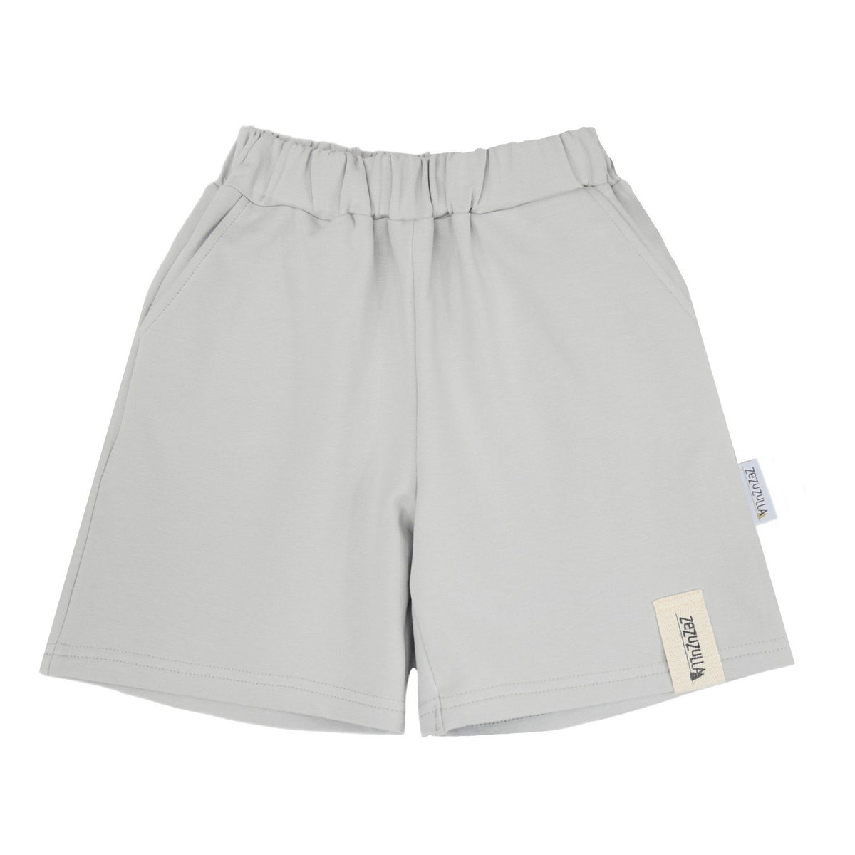 4. Flat lay of kids' grey cotton shorts by Zezuzulla featuring elastic waistband and side pockets, made from 92% OEKO-TEX cotton and 8% elastane, showcasing brand tag on clean background