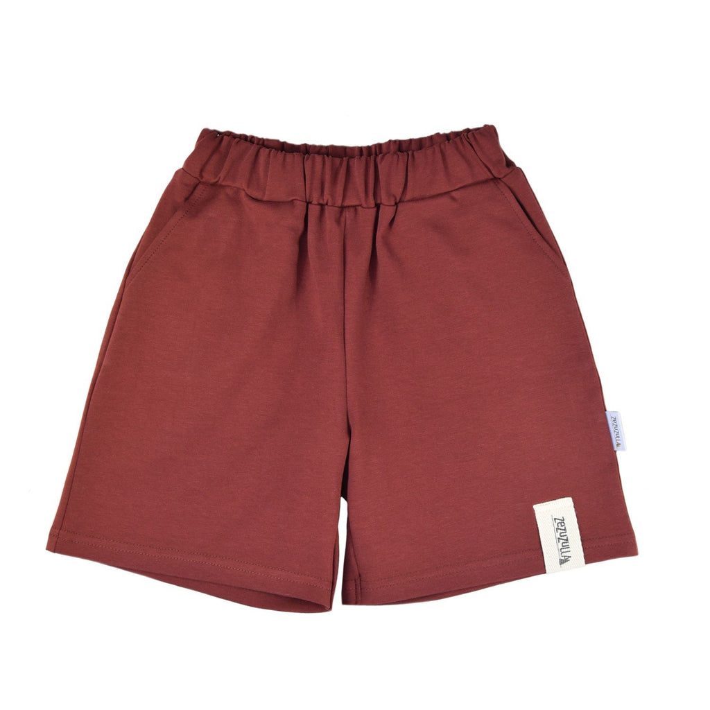 1. Kids rust-colored cotton shorts with elastic waistband and pockets, shown in a flat lay on a white background