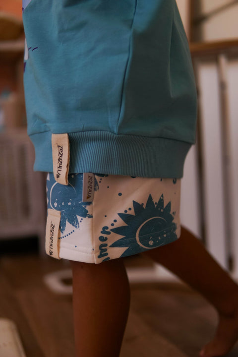 5. Detail of white shorts with blue sun print and Zezuzulla tags on child indoors