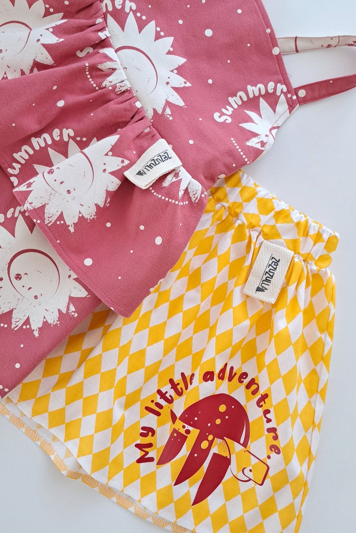 4. Flat lay of yellow and white diamond-patterned skirt with red turtle print next to a pink sun-printed dress
