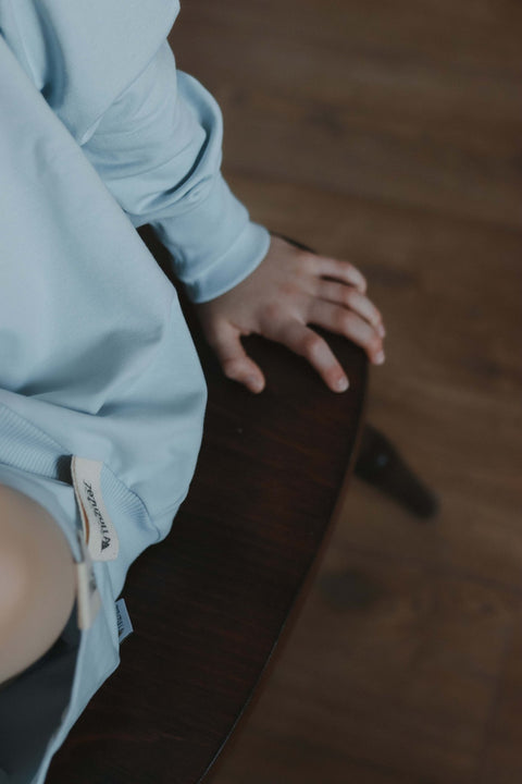 3. Close-up of Zezuzulla sweatshirt sleeve and tag on wooden chair