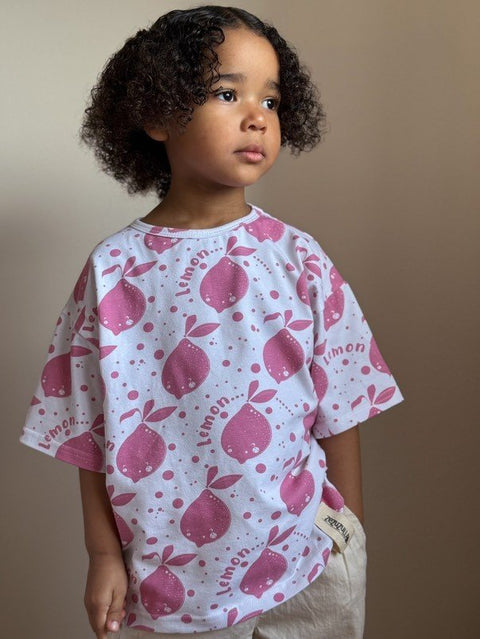 1. Child wearing Zezuzulla white T-shirt with pink lemon print, standing against neutral background