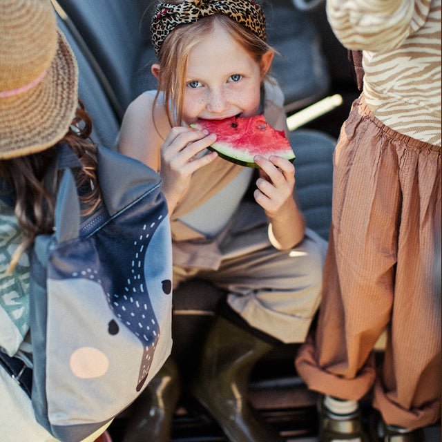 4. Close-up of girl with Muni wolf backpack, enjoying a snack in a car