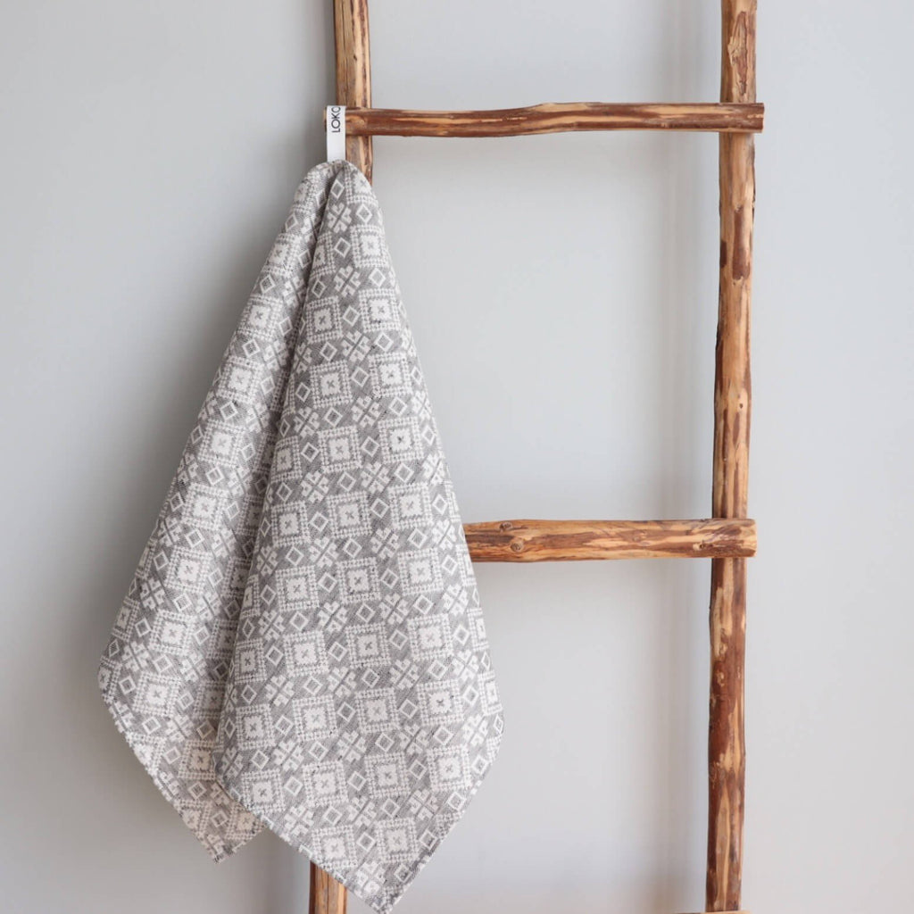 1. Grey kitchen towel with Kodavere folk art pattern hanging on wooden ladder, showcasing LOKO brand tag