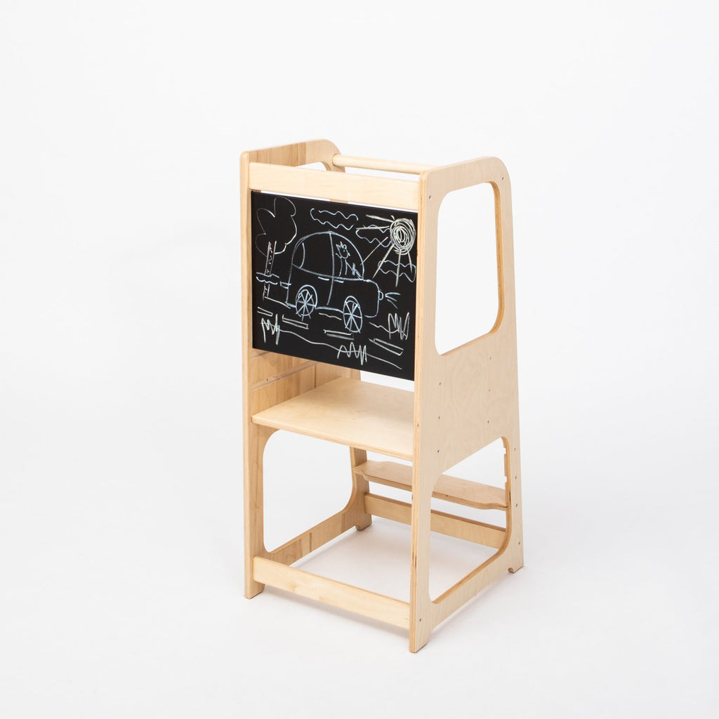 2. Natural wood Montessori kitchen helper tower with blackboard panel featuring car drawing, shown in a studio setting