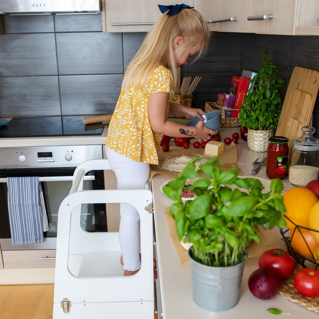 2. Girl using white kitchen tower to reach countertop while preparing food in kitchen