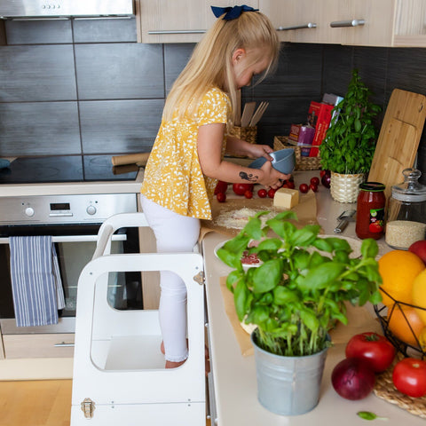 2. Girl using white kitchen tower to reach countertop while preparing food in kitchen
