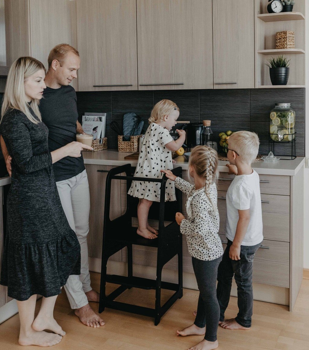 1. Family with children using black Montessori kitchen helper tower in kitchen, engaging in cooking activity