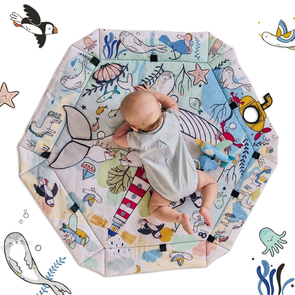 3. Baby lying on Kinderkraft Smartplay Sea playmat with underwater design and plush toys