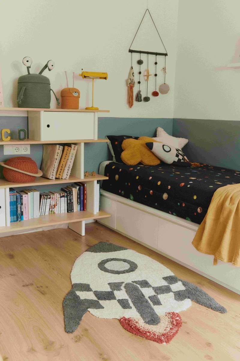 1. Knitted rocket pillow in natural and dark gray with colorful fringes in a child's room with space-themed decor