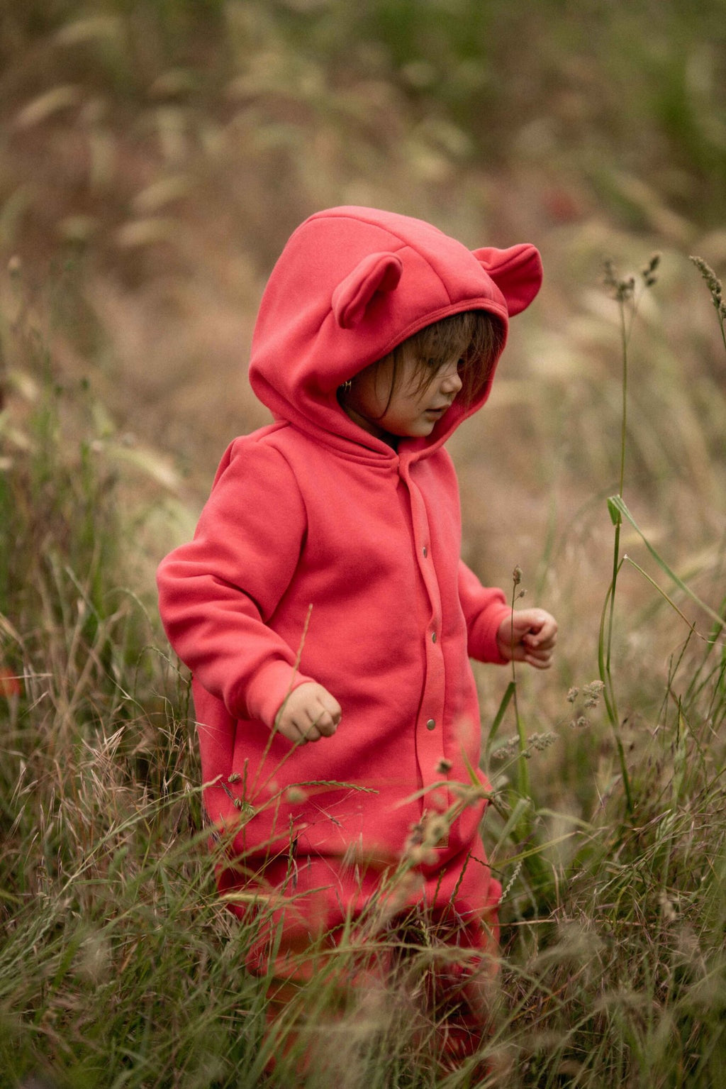 3. Child exploring in tall grass wearing coral eared jumpsuit by Zezuzulla