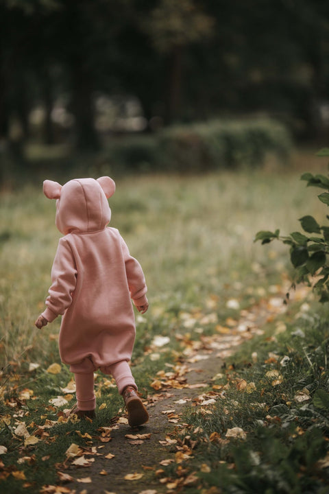 1. Child walking away in peach eared jumpsuit on a leaf-strewn path
