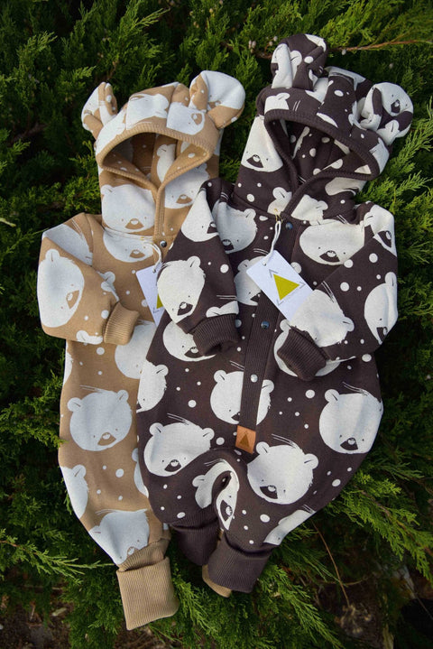 1. Two eared jumpsuits for babies in chocolate and beige polar bear print, displayed on greenery