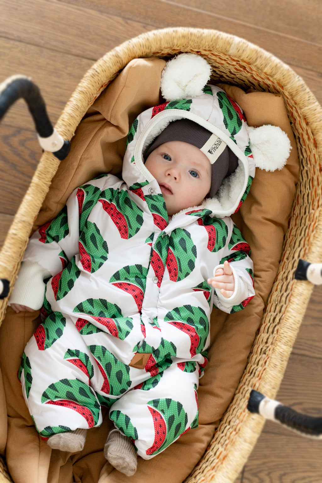 3. Baby in Zezuzulla watermelon print jumpsuit with teddy ears hood, lying in wicker basket