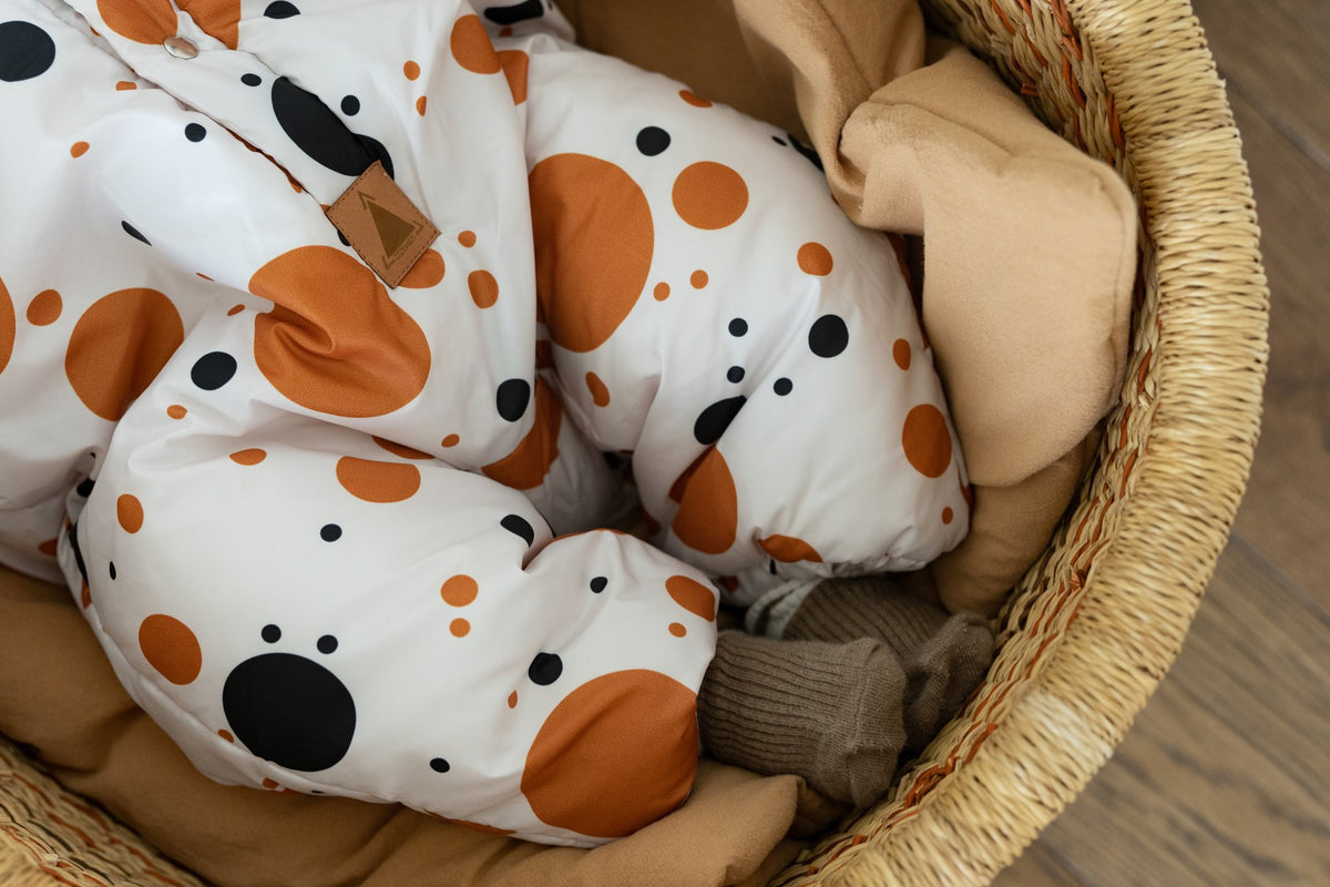 3. Close-up of black and orange polka dot fabric on winter jumpsuit for babies, showing leg detail
