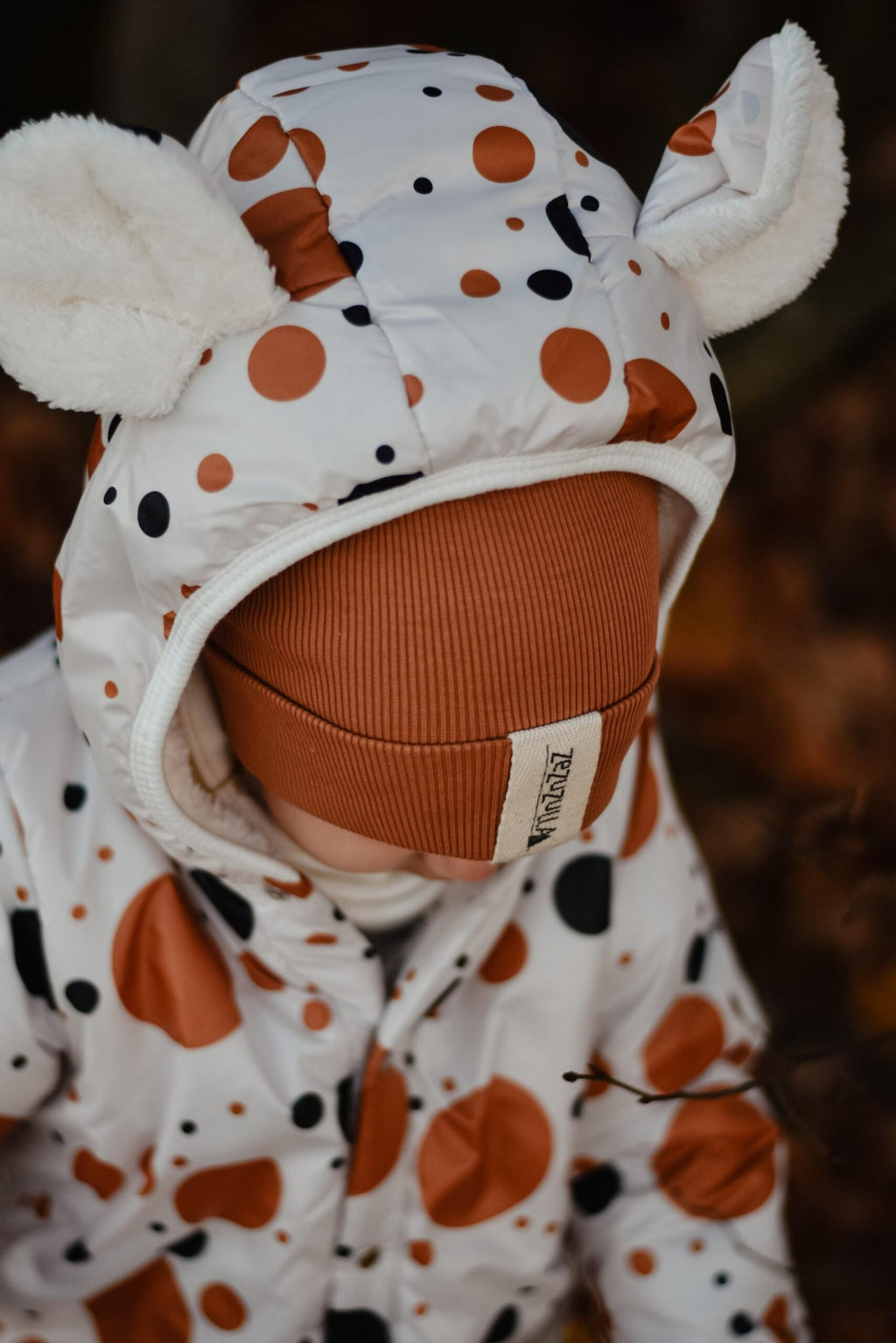 3. Close-up of hood with teddy bear ears on black and orange polka dot winter jumpsuit for kids