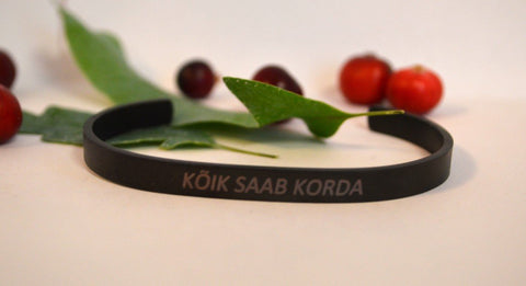 1. Men's black bracelet with engraved text 'KÕIK SAAB KORDA', styled with leaves and berries
