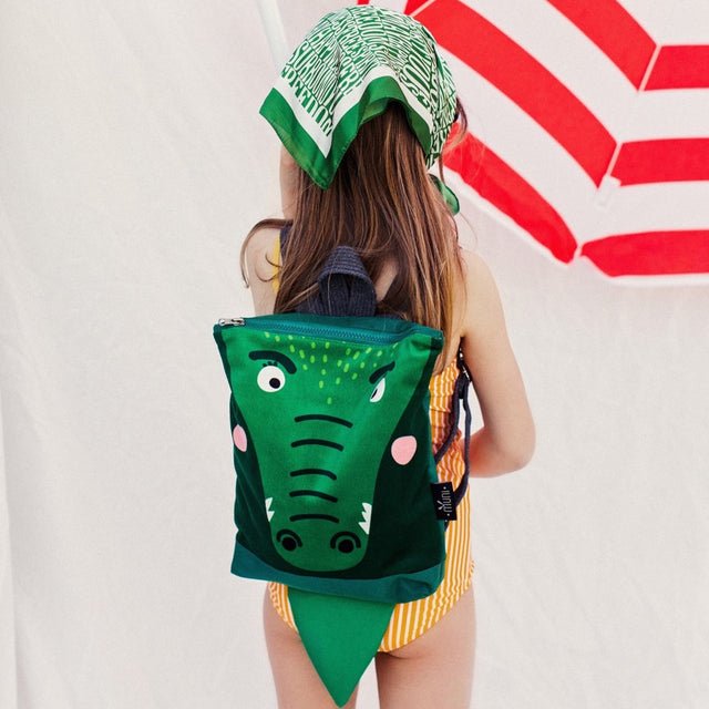 1. Girl wearing Muni crocodile backpack in outdoor setting with umbrella