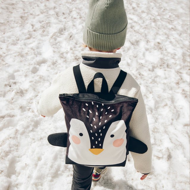7. Child with Muni Penguin backpack exploring snowy terrain