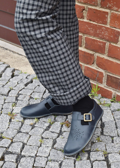 2. Close-up lifestyle shot of Kuuda Shoes in dark blue with adjustable buckle, worn with checkered pants