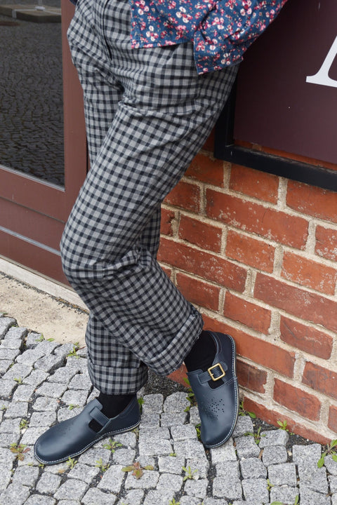 1. Lifestyle image of Kuuda Shoes in dark blue worn by a person with checkered pants, showcasing comfort and style