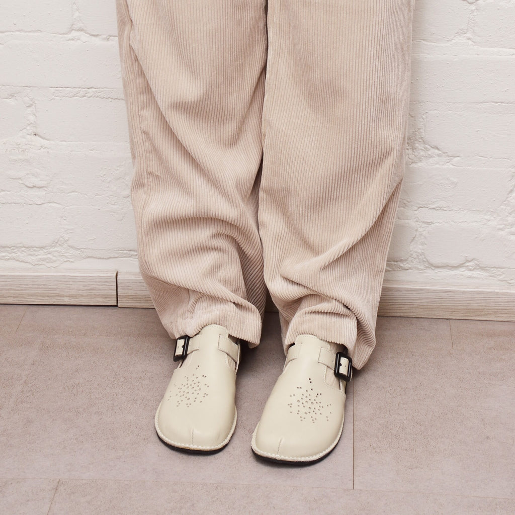 2. Close-up of Omaking Kuuda Shoes in white worn by a woman with beige corduroy pants, showing front view