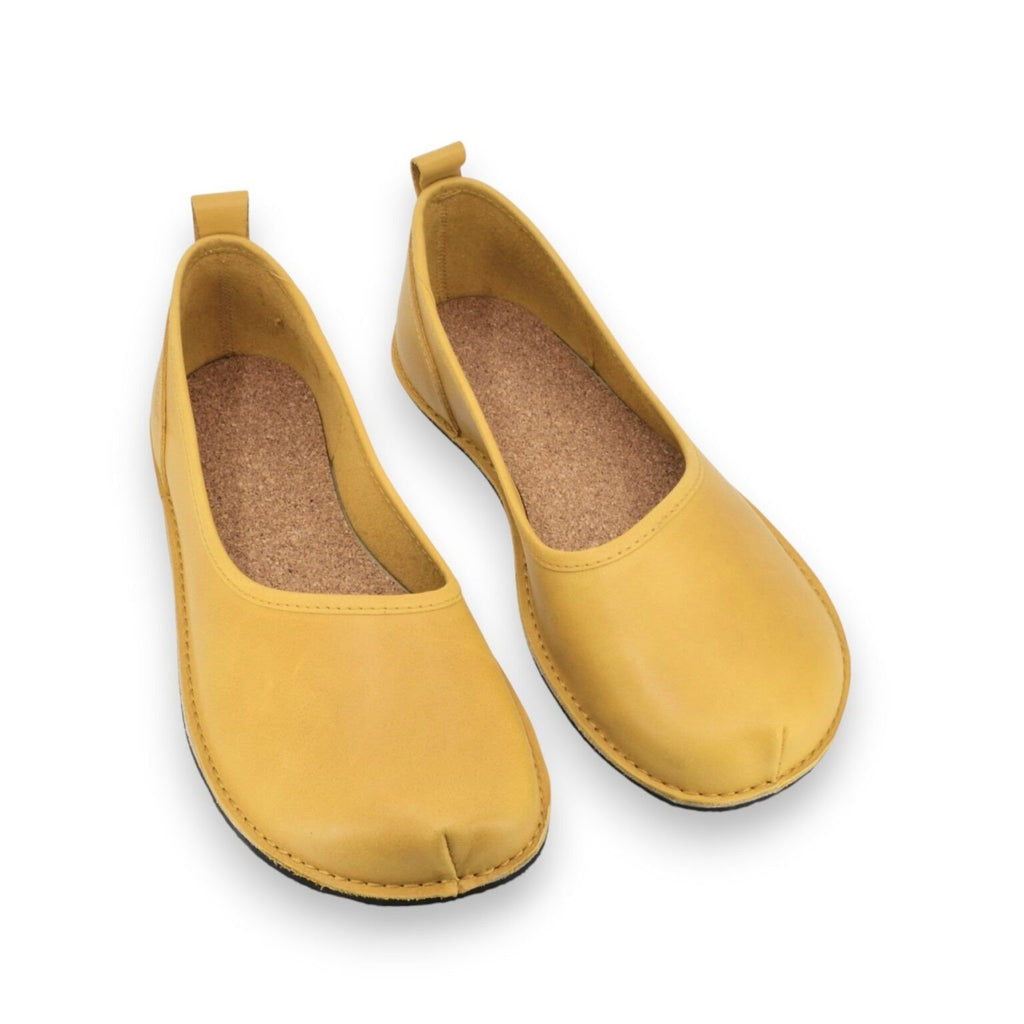 2. Pair of women's Kuutsid Shoes Wide in yellow, highlighting the natural cork insole and wide toe design, displayed in a studio setting