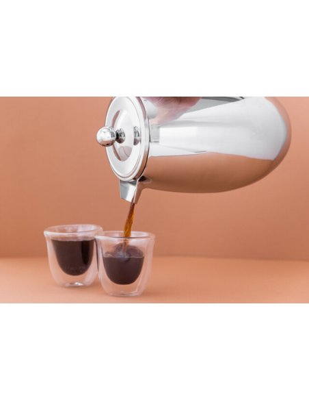 3. Pouring coffee from La Cafetière silver coffee maker into glass cups on peach background