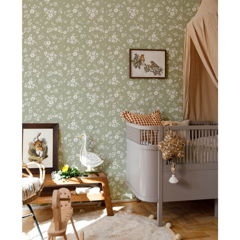 1. Nursery room with green floral wallpaper, grey crib, and wooden toys creating a cozy, vintage atmosphere