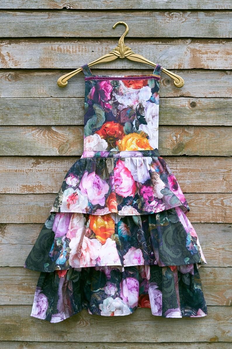 4. Dark floral apron with ruffles hanging on a wooden wall, showcasing design
