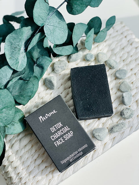 4. Flat lay of Nurme Detox Charcoal Face Soap with eucalyptus leaves and stones