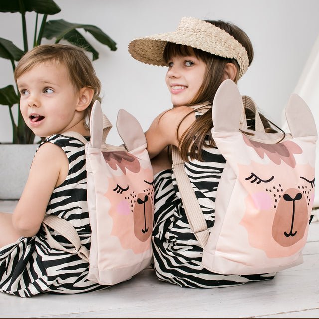 4. Two girls sitting with Muni llama backpacks, emphasizing playful design and comfort