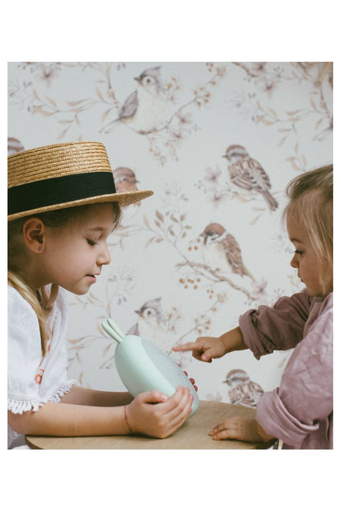 4. Two children interacting with green Rabbit & Friends lamp with alarm clock, in room with bird wallpaper