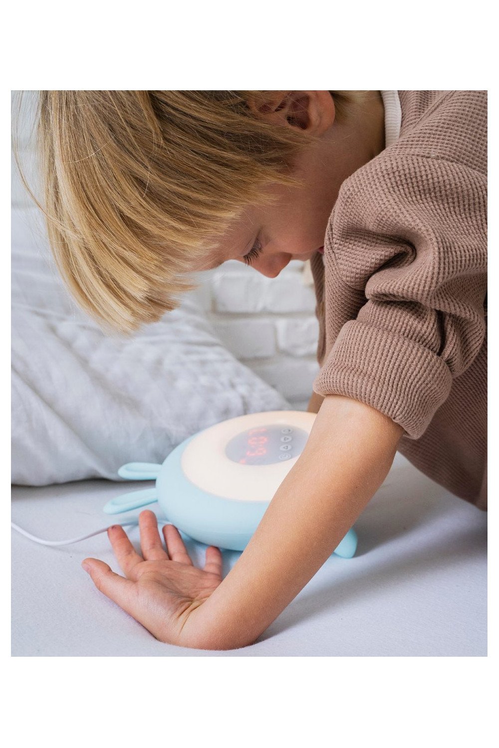 5. Child leaning over blue Rabbit & Friends alarm lamp with ears, displaying digital time, in bedroom