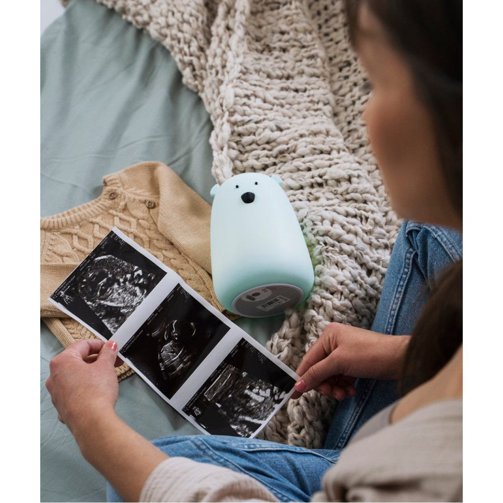 1. Woman looking at ultrasound images with blue teddy bear lamp on bed