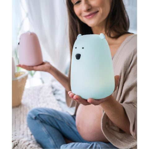 1. Pregnant woman holding blue teddy bear lamp in cozy home setting