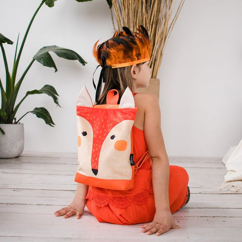 5. Girl wearing Muni fox backpack, side view in indoor setting with playful decor