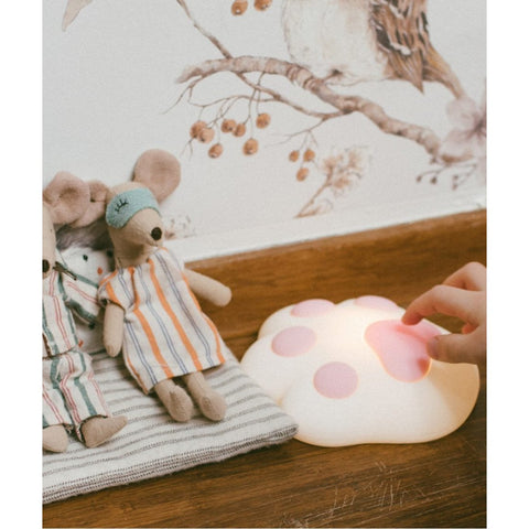 3. Close-up of pink paw-shaped silicone lamp on wooden floor next to toy mice in children's room